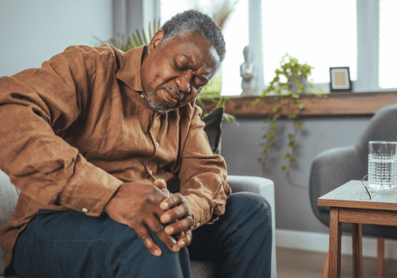 Man experiencing knee pain on couch