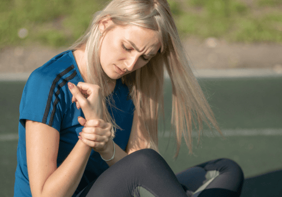 Blond woman examining her wrist injury