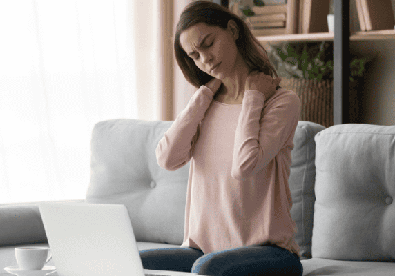 Woman massaging neck while sitting on couch
