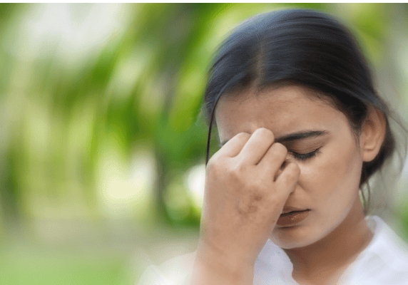Pensive woman touching forehead outdoors