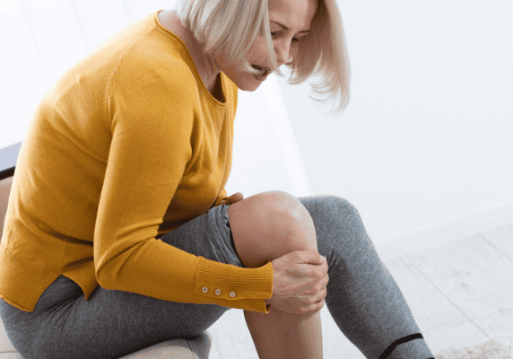 Woman holding knee in discomfort