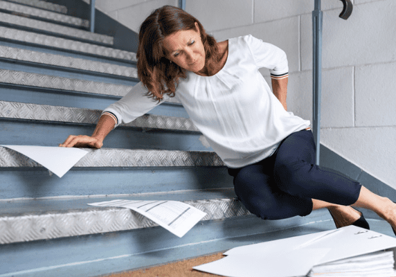 Lady slips on staircase, holding back