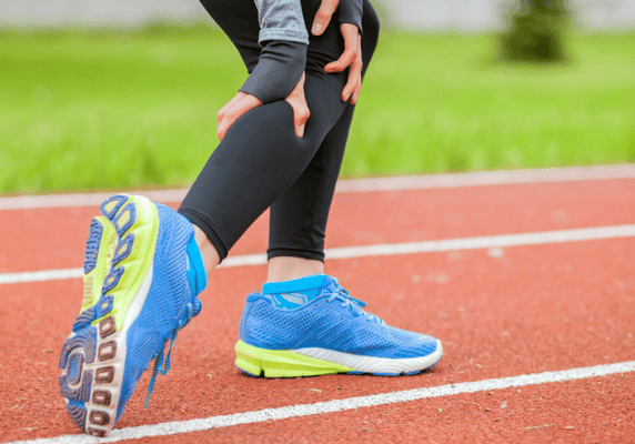 Runner stretching on track with blue shoes