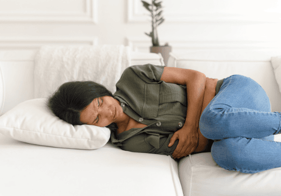 Woman experiencing discomfort on white couch