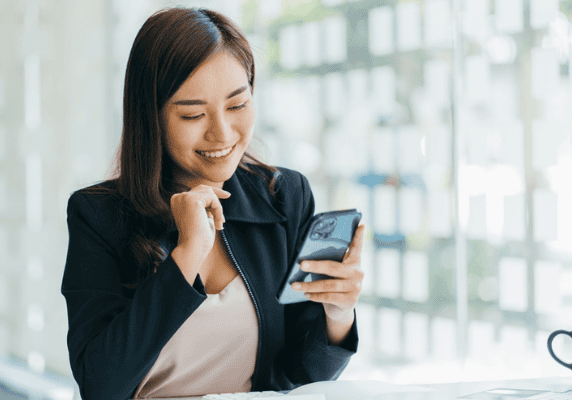 Woman smiling at phone in office