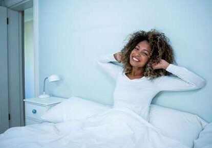 Woman stretching in bed, smiling brightly